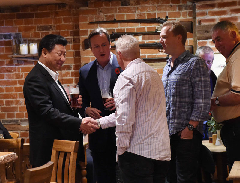 這是習(xí)近平與卡梅倫飲啤酒，並同當(dāng)?shù)孛癖娊徽?。新華社記者 饒愛(ài)民 攝