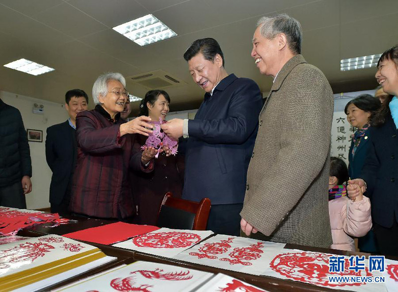 這是15日上午，習(xí)近平在西安市雁塔區(qū)電子城街道二〇五所社區(qū)服務(wù)中心欣賞社區(qū)老人的剪紙作品。 新華社記者 李濤 攝